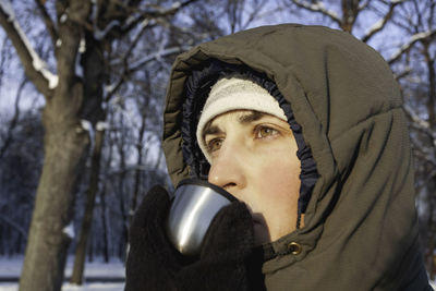 Man drinks hot tea from metal thermos. leisure activity in winter forest at sunset.