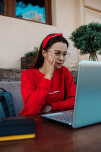 Midsection of woman using phone while sitting on table