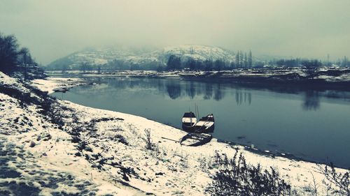 Scenic view of lake by snowcapped mountains against sky