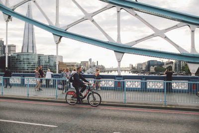 Person riding bridge over river in city