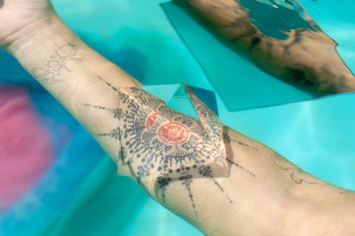 Cropped image of woman with prism on tattoo underwater