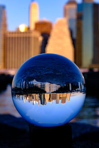 Close-up of crystal ball against building in city