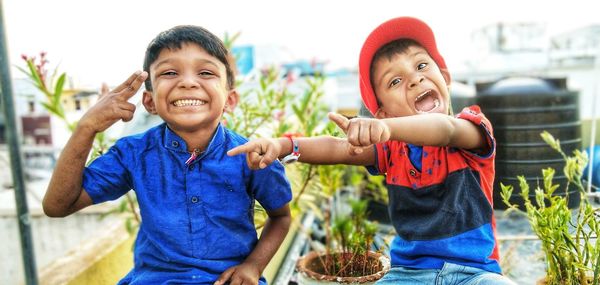 Portrait of cheerful brothers sitting outdoors