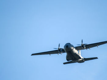 Low angle view of airplane flying against clear blue sky