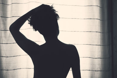 Rear view of woman standing against wall