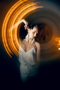 Dancer poses on a dark background in a bright halo.