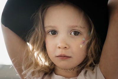 Close up portrait of a young girl with her face painted and a hat on