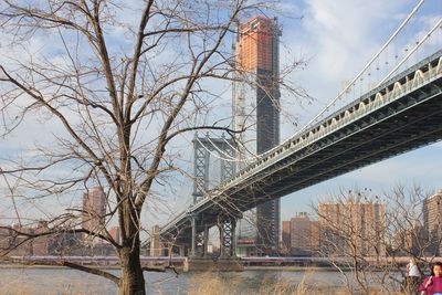 Low angle view of bridge over river in city against sky