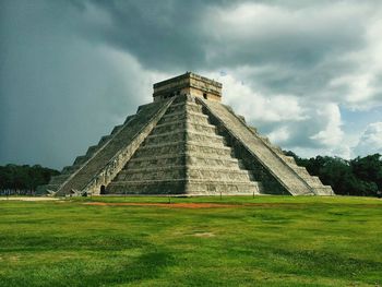 Historic chichen itza on green field against sky