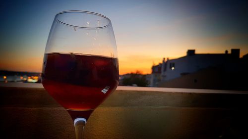 Close-up of beer glass against sky during sunset