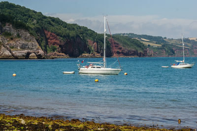 Sailboats in sea against sky