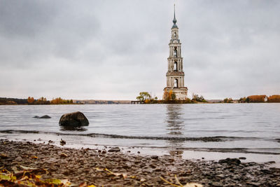 View of building at beach against cloudy sky