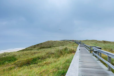 Footbridge on grassy hill leading towards sea