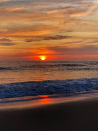 Scenic view of sea against dramatic sky during sunset