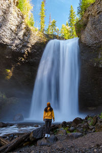 Rear view of woman standing against waterfall