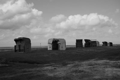 Abandoned huts on field against sky