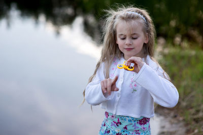 Cute girl spinning fidget spinner at lakeshore