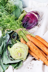 High angle view of fresh vegetables and dirt on white fabric