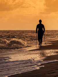 Silhouette woman on beach against sky during sunset