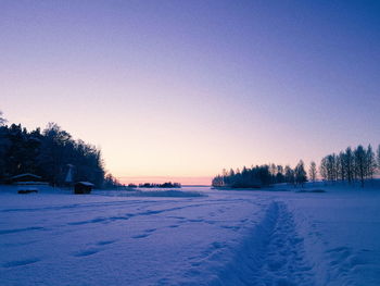 Scenic view of snow covered field against clear sky during sunset