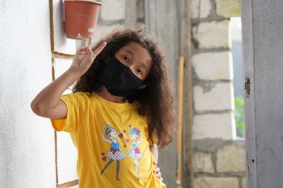Full length of girl standing against yellow wall