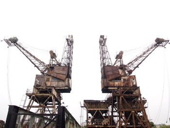 Low angle view of crane at construction site against clear sky