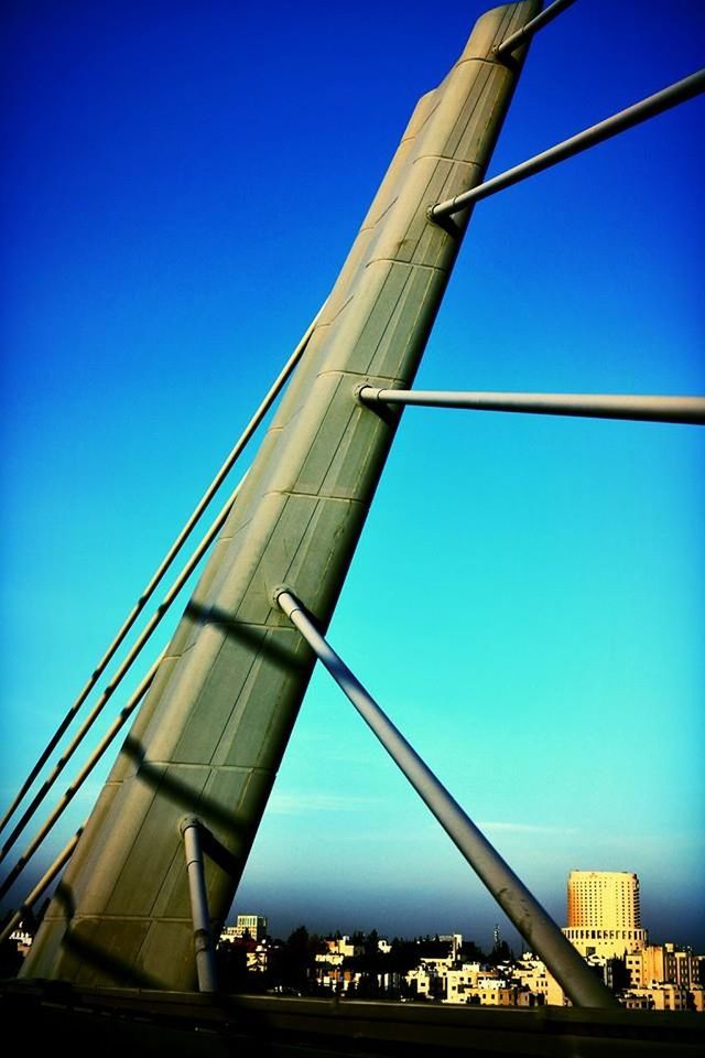 clear sky, architecture, built structure, blue, low angle view, connection, building exterior, copy space, bridge - man made structure, engineering, bridge, cable, suspension bridge, day, transportation, outdoors, no people, city, sunlight, metal