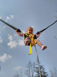 Low angle view of girl bungee jumping against blue sky