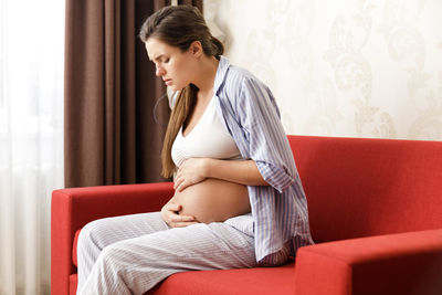 Young woman sitting on sofa at home