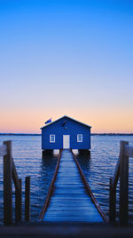 Built structure by sea against clear sky at sunset