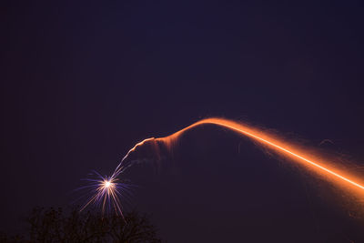 Low angle view of illuminated fireworks against sky at night