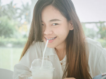 Portrait of smiling young woman drinking glass
