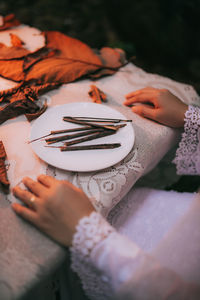 Midsection of woman with sticks in plate on table