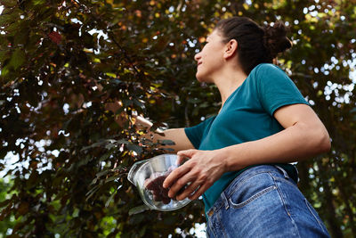 Low angle view of young woman standing against plants