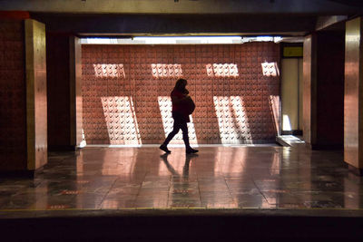 Rear view of man walking in corridor of building