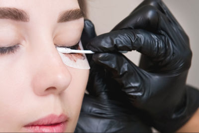 Makeup artist performs the procedure of lamination and coloring of eyelashes on a beautiful woman in