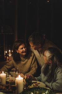 Senior woman talking to female friends at candlelight dinner party