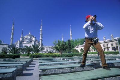 Man standing by building against clear sky