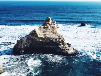 Rock formation in sea against sky