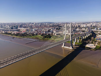 High angle view of bridge over river by buildings in city against sky