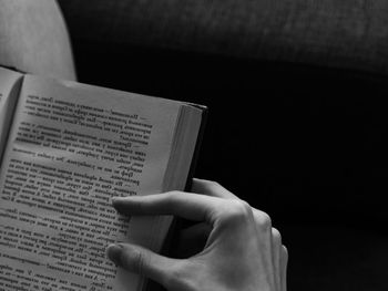 Cropped hand of man reading book