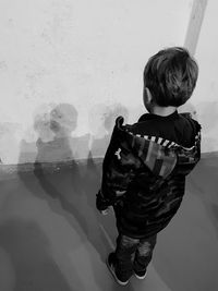 Rear view of boy standing against glass wall