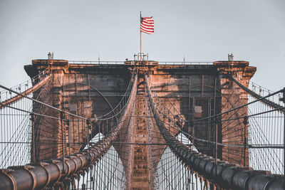 Low angle view of flags on bridge against sky