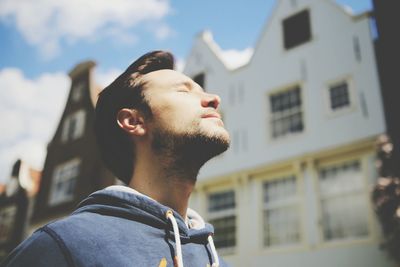 Low angle view of man with closed eyes against building