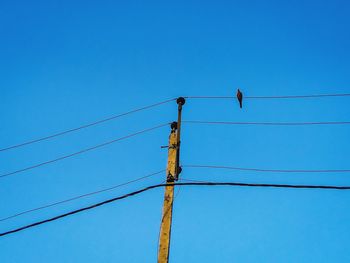 Low angle view of power lines against clear blue sky