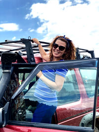 Young woman wearing sunglasses while sitting on car