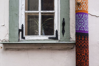 Rolled colorful fabric by closed window of building