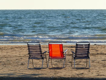 Chairs on beach against sky