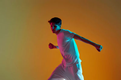 Side view of young man playing tennis