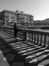 People walking on railing against buildings in city